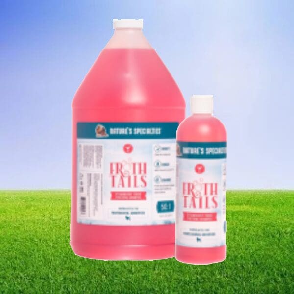 A bottle of pink liquid sitting on top of grass.